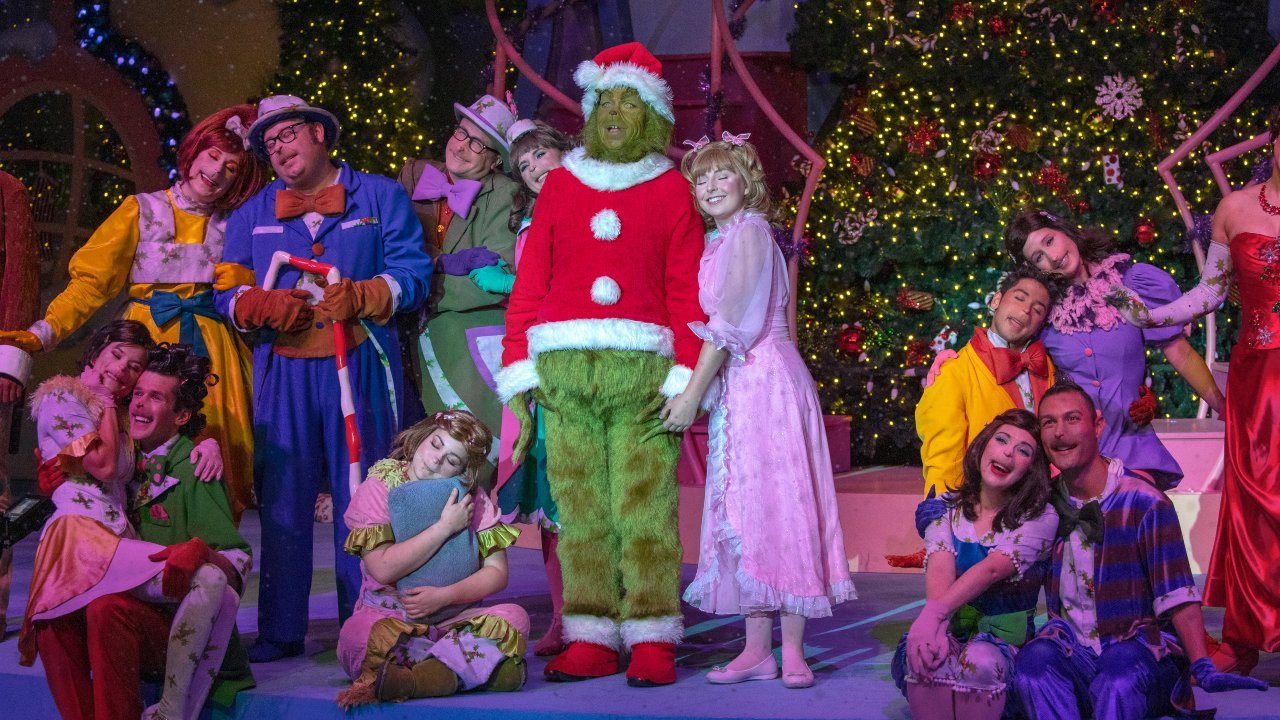 Grinch posing with costumed performers