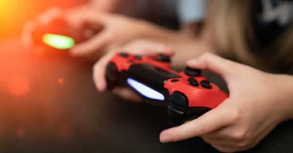 Hands holding gaming controller on sofa