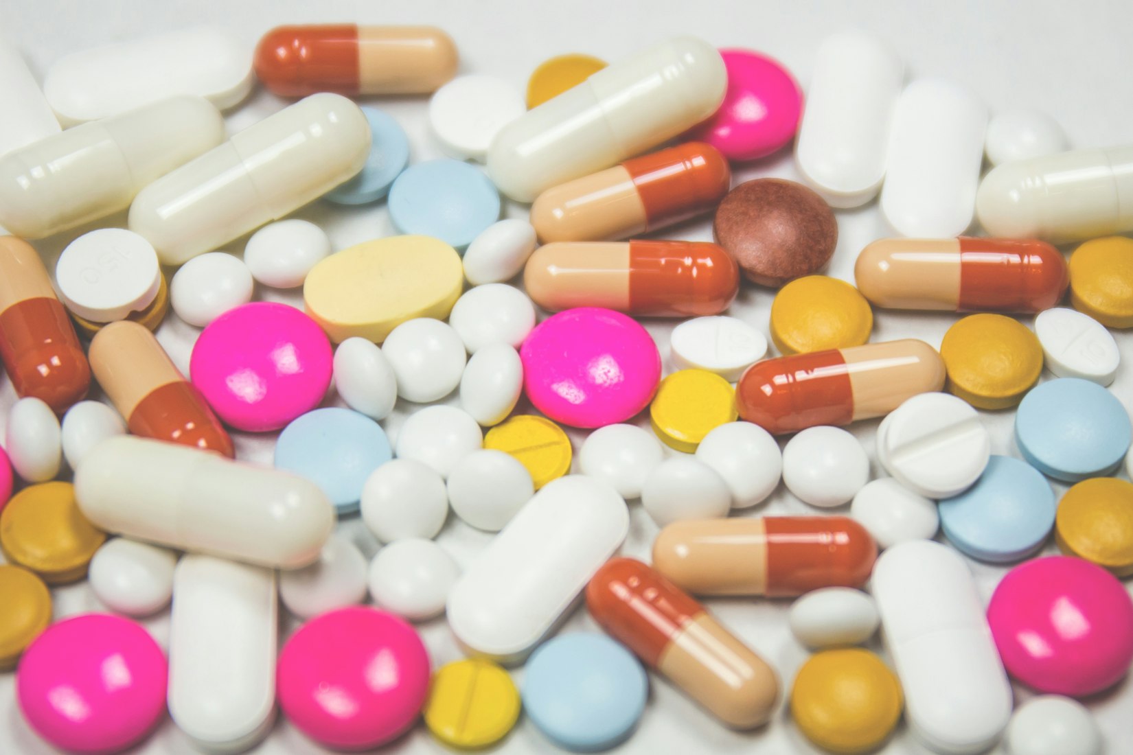 Colorful pills scattered on white surface